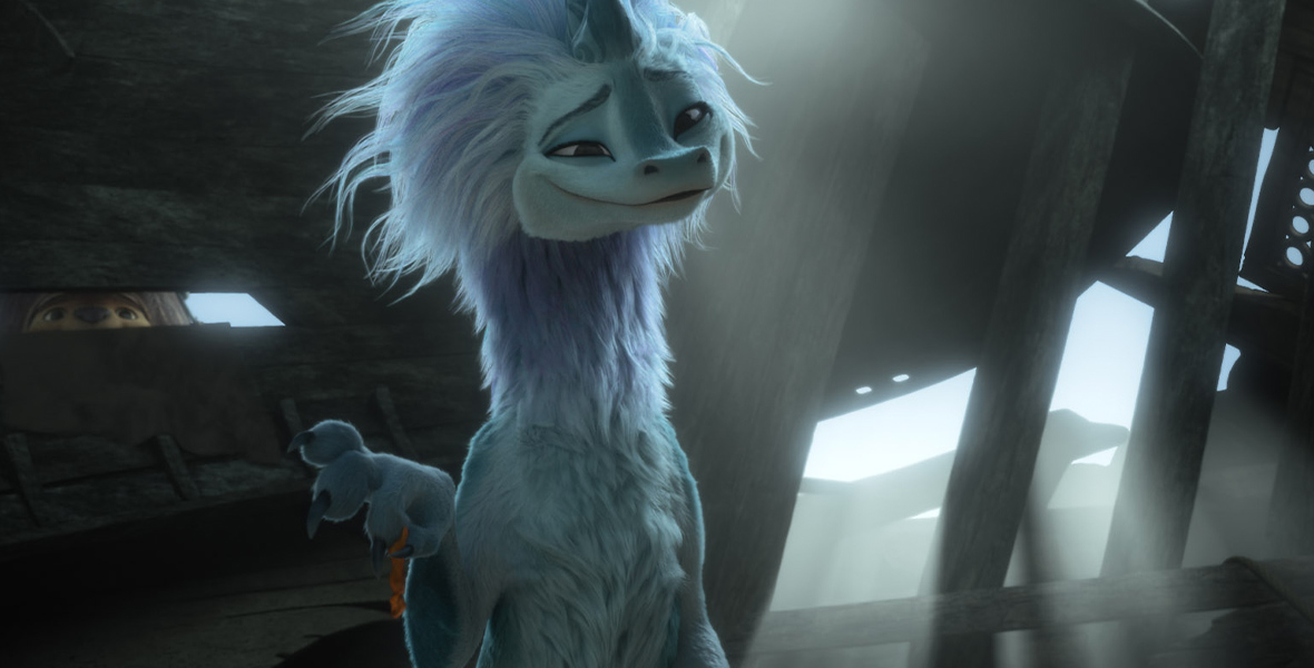 Sisu, a fuzzy blue dragon, is smiling. In the background, Tuk Tuk, an armadillo mutant, peers through the wooden planks while looking at Sisu.